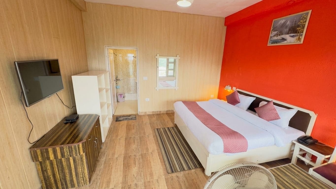 Una habitación de hotel con cama, escritorio, televisor y zona de ducha.