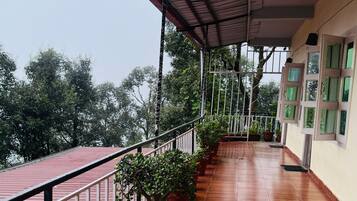 A covered balcony with potted plants and a wooden floor.