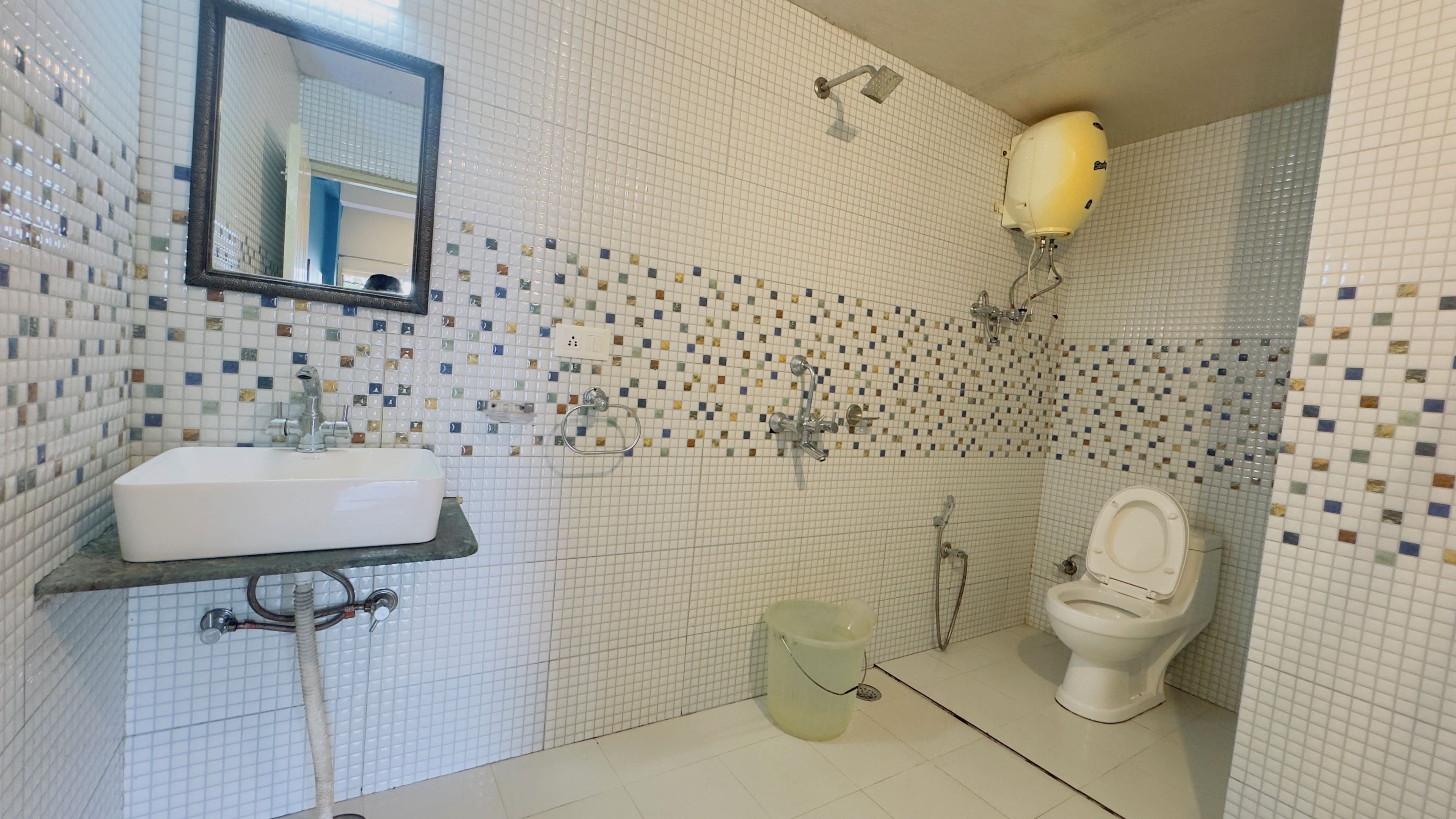 A bathroom with a white sink, a mirror, a toilet, and a shower area.