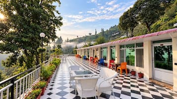 A hotel corridor with checkered flooring, outdoor seating, and a view of a lake.