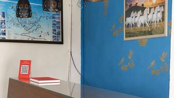 A reception desk with a blue wall and a framed picture of horses.