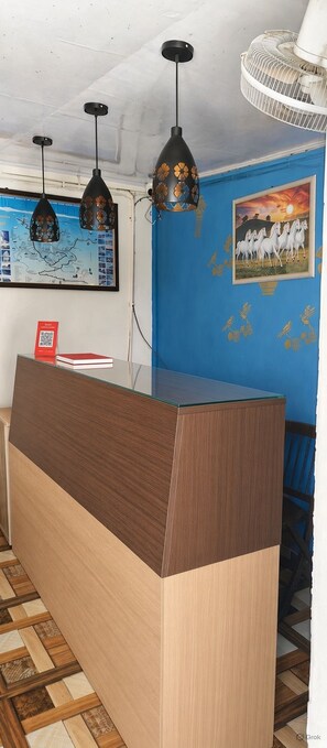 A reception desk with a blue wall and a framed picture of horses. - The Sky Hotels (Mussoorie)
