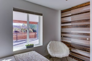 Ein Zimmer mit einem großen Fenster, einem weißen, flauschigen Sessel und einer Wand aus Hol zleisten.
