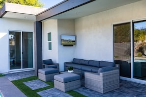 Ein stilvoller Außenbereich mit einer Couch, zwei Sesseln und einem Couchtisch.