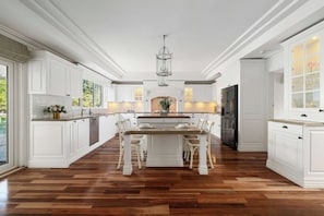 A spacious kitchen with white cabinetry, a central island with seating, and a large refrigerator. - Shalom Garden Luxury Estate · Pool, Tennis Court (Melbourne)