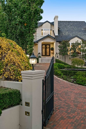A gated entrance to a residential property with a brick pathway leading to the front door. - Shalom Garden Luxury Estate · Pool, Tennis Court (Melbourne)