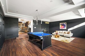 Una sala de estar moderna con una mesa de billar, un sofá y una escalera.