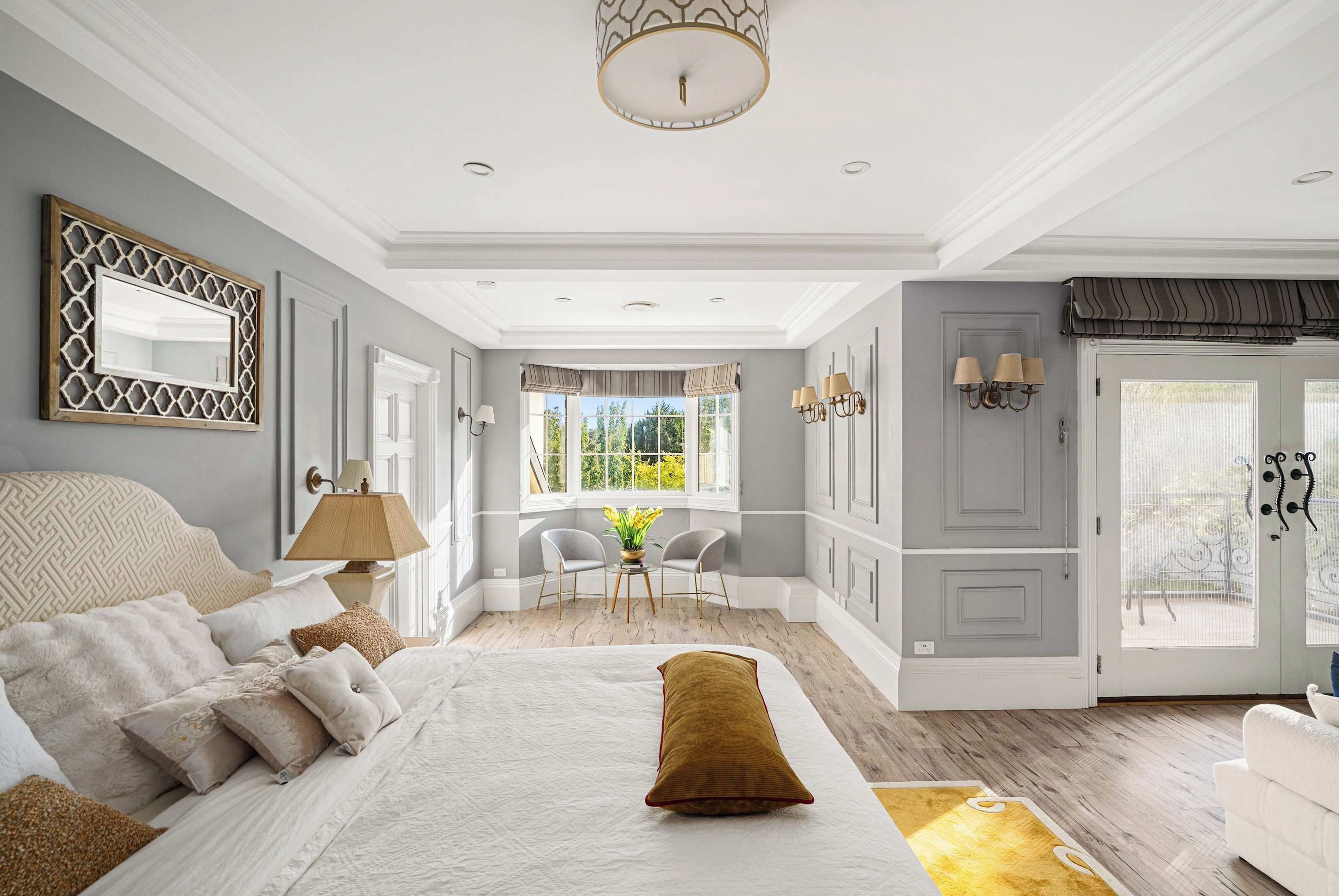 Une chambre à coucher avec un grand lit, un coin salon avec des fauteuils, une fenêtre avec des rideaux et une porte également dotée d’un rideau.