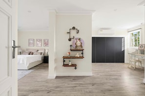 A bedroom with a bed, bedside table, lamp, and wall-mounted shelves with decorative items.