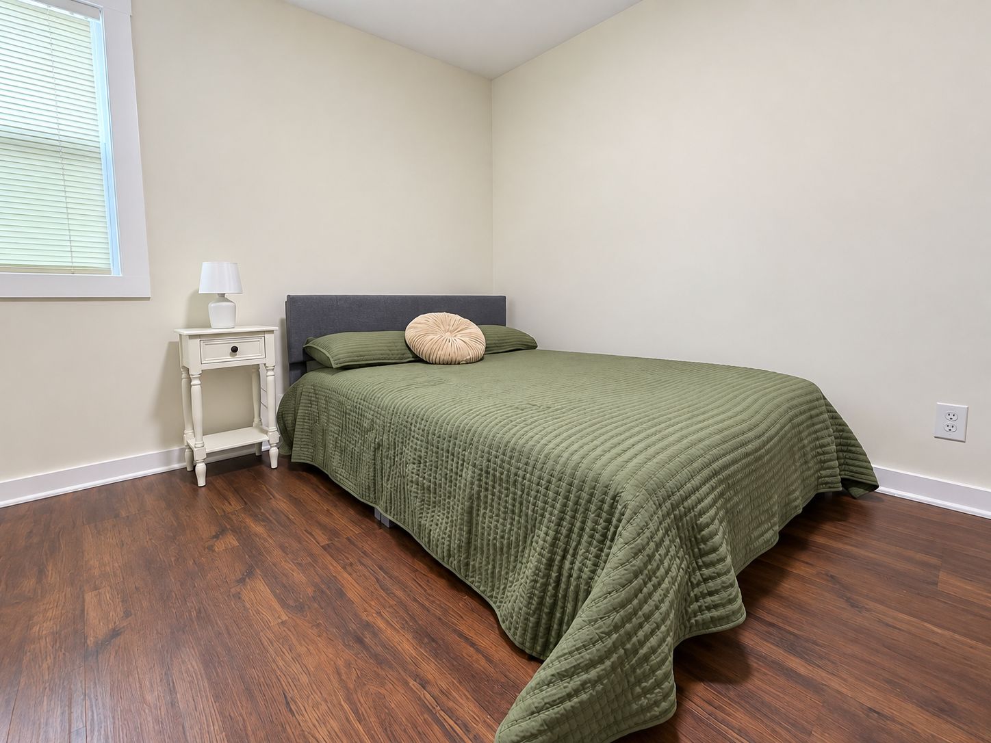 Une chambre à coucher avec un lit, une table de chevet et une fenêtre.