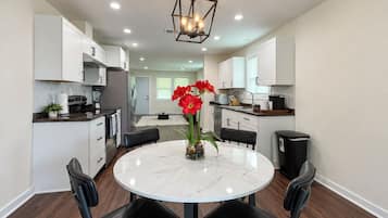 A modern kitchen with white cabinets, a round marble table, and black chairs.