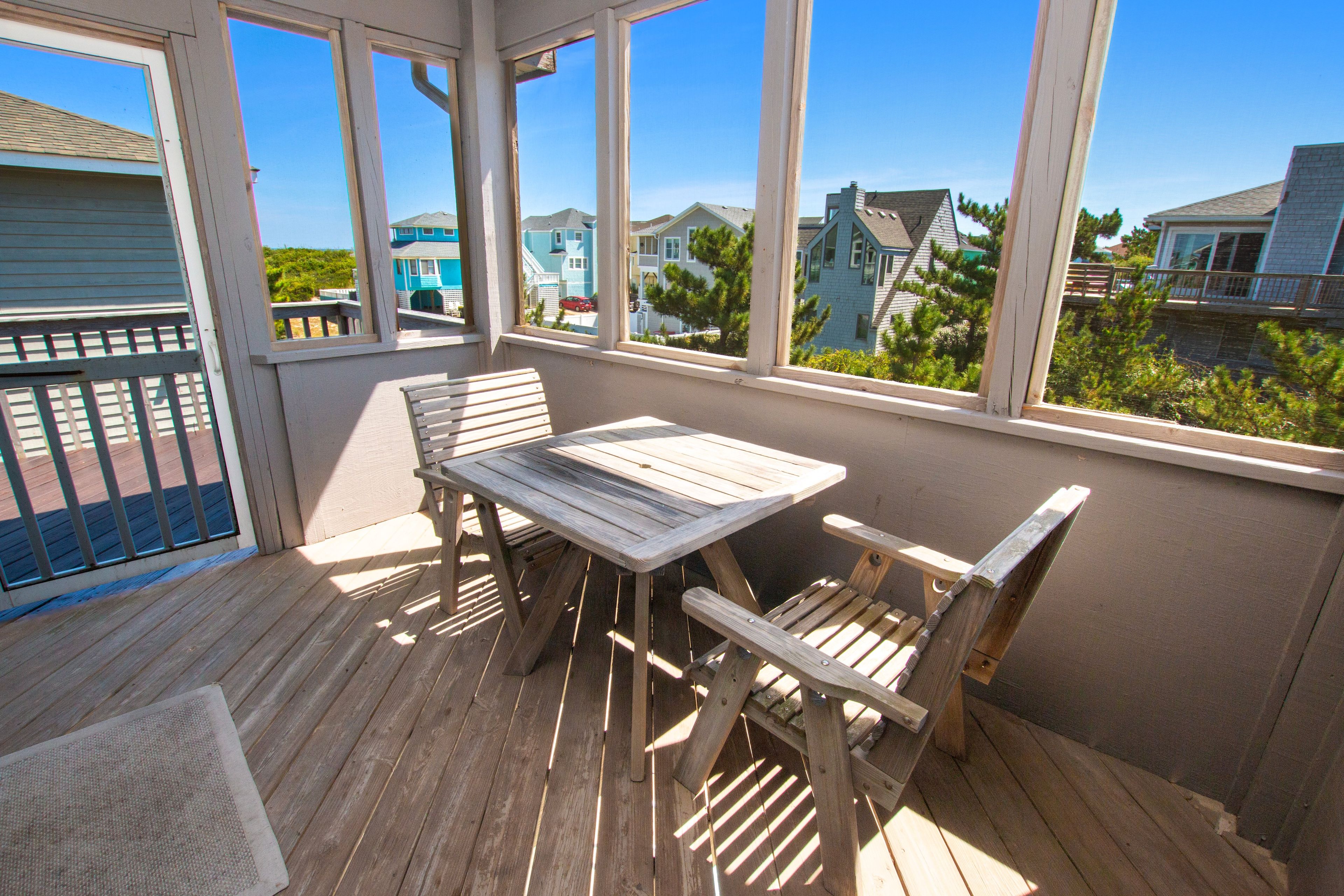 A wooden deck with a table and chairs, overlooking a residential area with houses.
