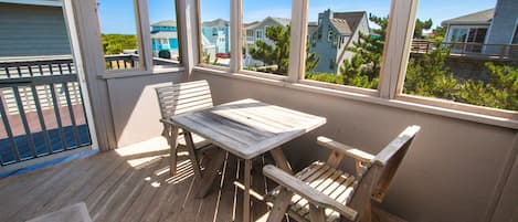 A wooden deck with a table and chairs, overlooking a residential area with houses.