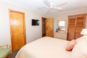 A bedroom with a bed, a dresser, a mirror, a television, and a ceiling fan. - Oceanside, Private Pool, Dogs Welcome-OS6Q, Koo Koo's Nest (Corolla)