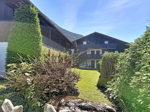 A building with a sloped roof, surrounded by well-maintained hedges and a grassy area. - Edelweiss by Interhome (Farchant)