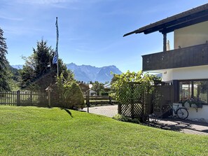 A residential property with a well-maintained lawn, a flagpole, a bicycle, and a mountain view in the background. - Edelweiss by Interhome (Farchant)