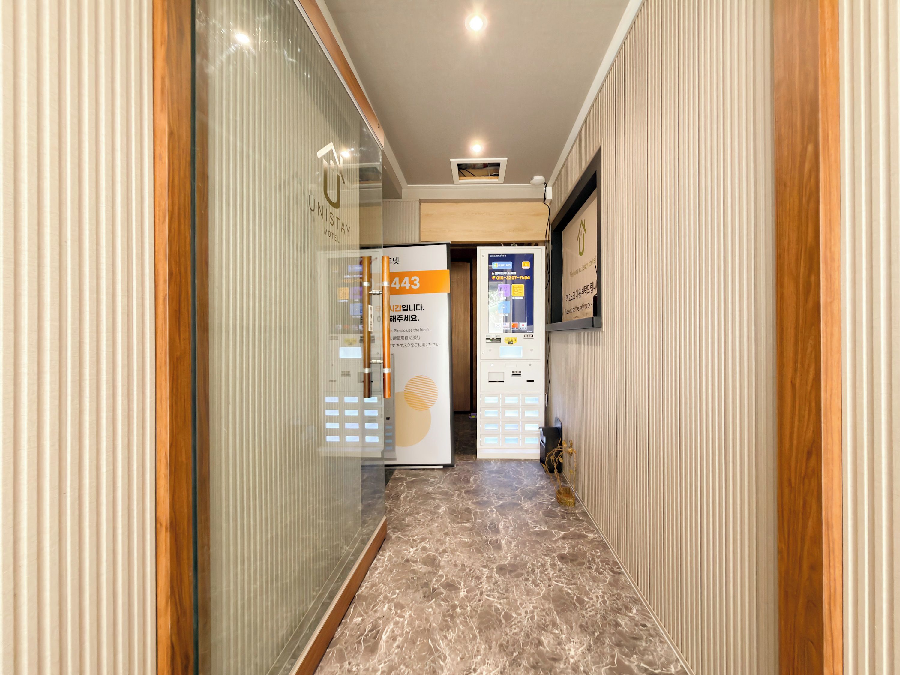 A hotel corridor with a reception desk, a vending machine, and a sign with the number 443.