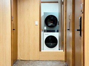 Un cuarto de lavado con lavadora y secadora, puertas de madera y piso de baldosas.