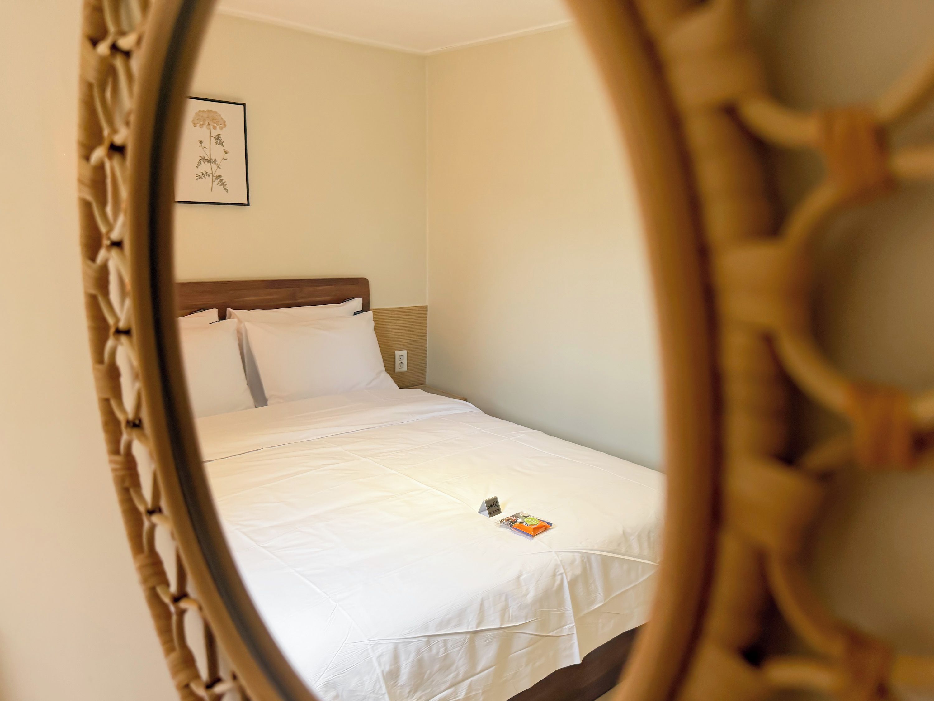 A single bed with white bedding, a wooden headboard, and a small bedside table with a book.