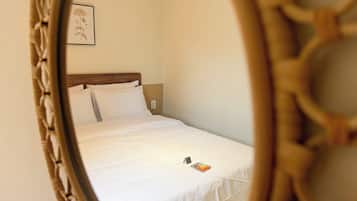 A single bed with white bedding, a wooden headboard, and a small bedside table with a book.