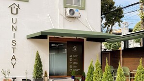 A hotel entrance with a sign reading 'UNISTAY HOTEL' and amenities listed such as 'No Smoking,' 'Free Wi-Fi,' and '24 Self Check-In.' - Unistay (Dongducheon)