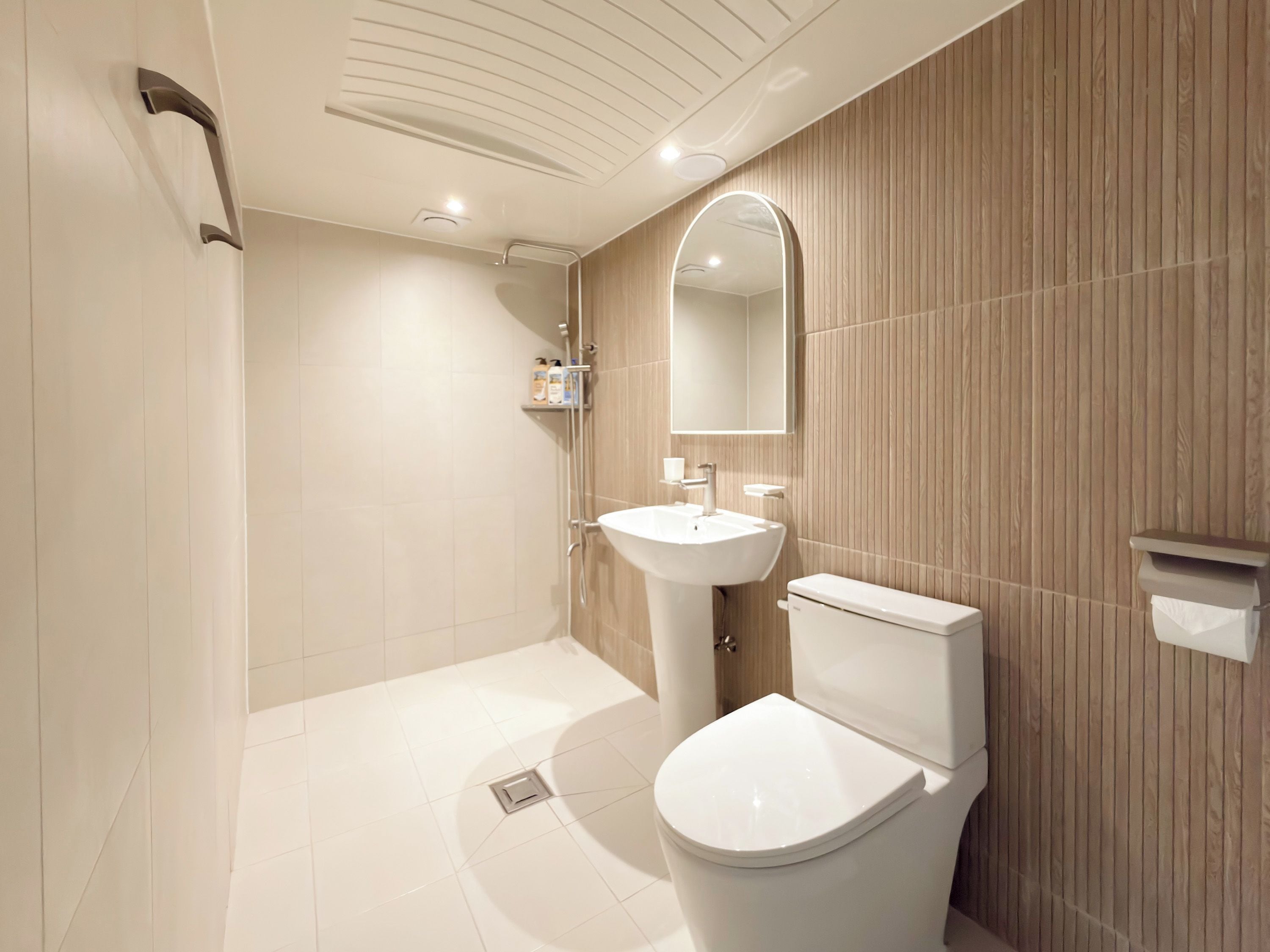 A modern bathroom with a shower, sink, toilet, and a mirror.