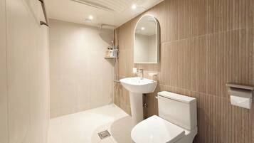 A modern bathroom with a shower, sink, toilet, and a mirror.