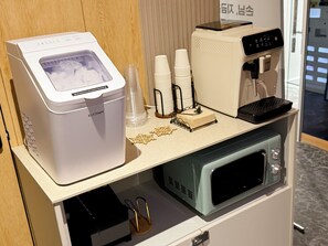 A kitchenette with a coffee machine, microwave, and a small refrigerator.