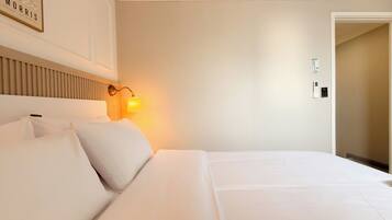 Quarto de hotel com cama, luminária na parede e uma porta.