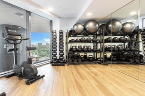 A gym with exercise equipment, a treadmill, and a view of buildings. - Million Dollar Views - Luxe 62nd Floor Apartment (Brisbane City)