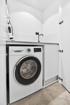 A compact, modern laundry room with a Bosch washing machine, a drying rack, and a small sink. - Million Dollar Views - Luxe 62nd Floor Apartment (Brisbane City)