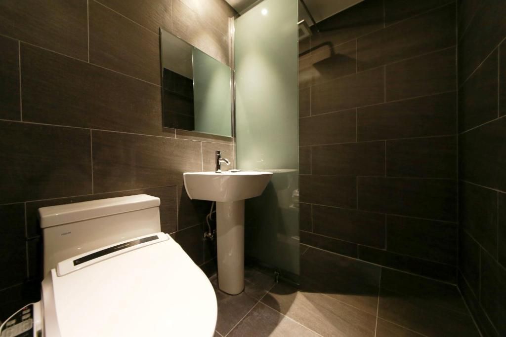 A modern bathroom with a toilet, sink, and a mirror.