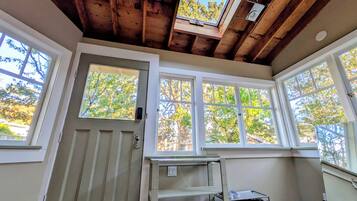 Una habitación con techo de madera, ventanas amplias, una puerta y un zapatero.