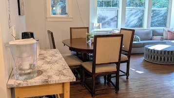 A dining area with a marble table, wooden chairs, and a chandelier.
