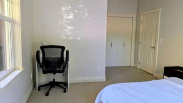 A bedroom with a bed, a chair, a closet, and a window.