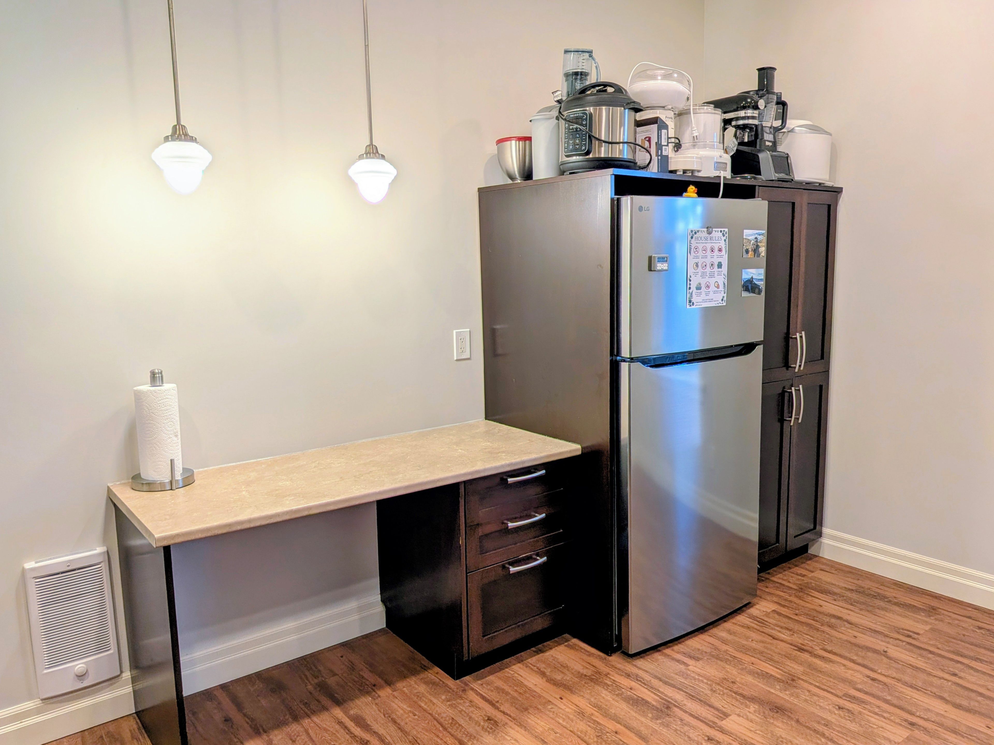 Cocina compacta con refrigerador empotrado, encimera y extractor de aire mural.
