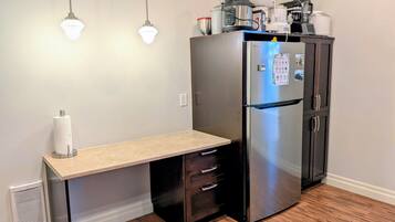 Cocina compacta con refrigerador empotrado, encimera y extractor de aire mural.