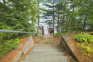 A set of stone steps leading up to a wooden deck with a boat docked at the end. - Private House with access to Stinson Lake! Enjoy lake life in style! (Rumney)