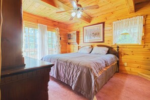 A wooden cabin bedroom with a bed, a ceiling fan, and a window with curtains. - Private House with access to Stinson Lake! Enjoy lake life in style! (Rumney)