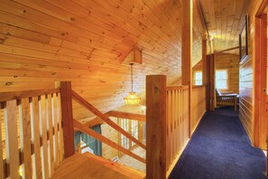 A wooden interior with a staircase leading to an upper level, a hanging light fixture, and a view through a window. - Private House with access to Stinson Lake! Enjoy lake life in style! (Rumney)