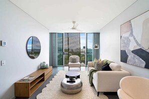 Ein modernes Wohnzimmer mit Sofa, Sessel, Couchtisch und einem großen Fenster mit Blick.