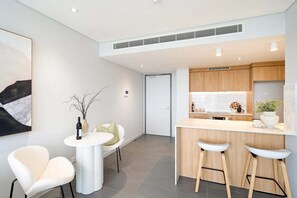 Eine moderne Küche mit Barbereich, weißen Barhocker und einem Esstisch mit Stühlen.