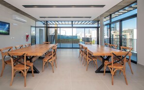 Uma sala de conferências com uma mesa comprida e cadeiras, janelas amplas e vista para a paisagem urbana.