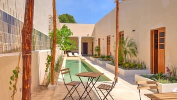 Zona piscina con pergola, posti a sedere e vista su un edificio sullo sfondo.