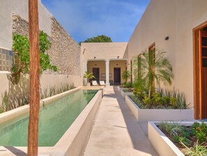 A pool area with a clear pathway, lounge chairs, and a building with a stone facade. - Studio w/private bathroom + pool / A+ Location (Merida)