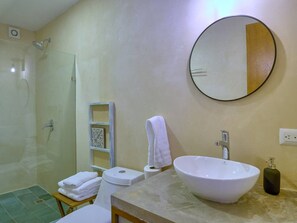 Ein Badezimmer mit Duschkabine, Waschbecken und großem Spiegel sowie einem Handtuchhalter.