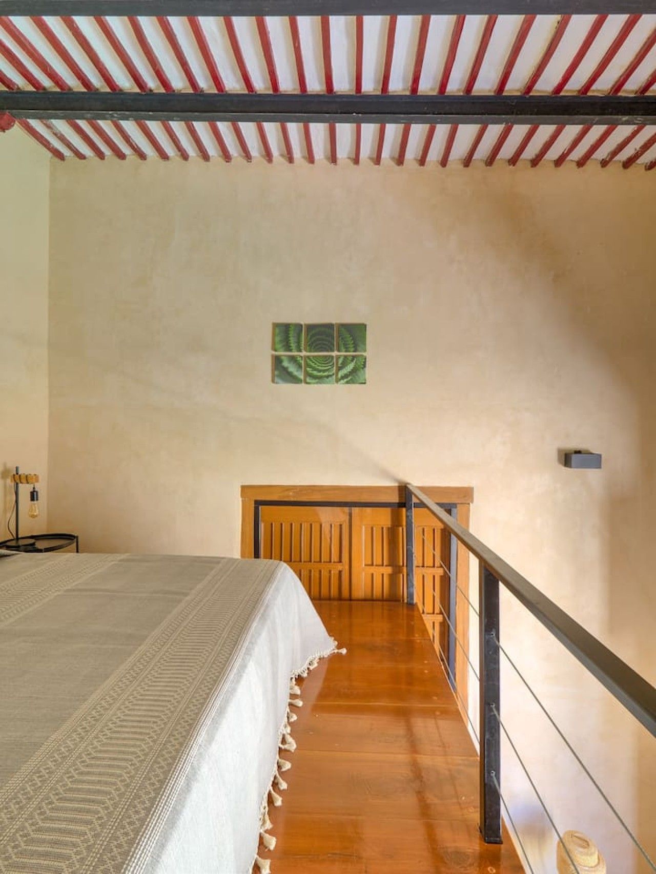 A bedroom with a bed, a wooden staircase, and a wall-mounted light fixture.