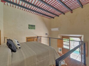 Ein Schlafzimmer mit einem Bett, einem Koffer, einer Treppe und Blick nach draußen.