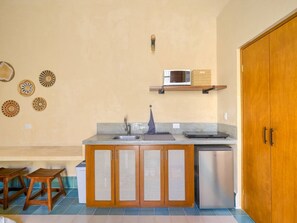 A compact kitchen with a sink, a microwave, and a small refrigerator. There are wooden stools and a wooden door. - Loft w/bathroom and kitchenette + accessibility (Merida)