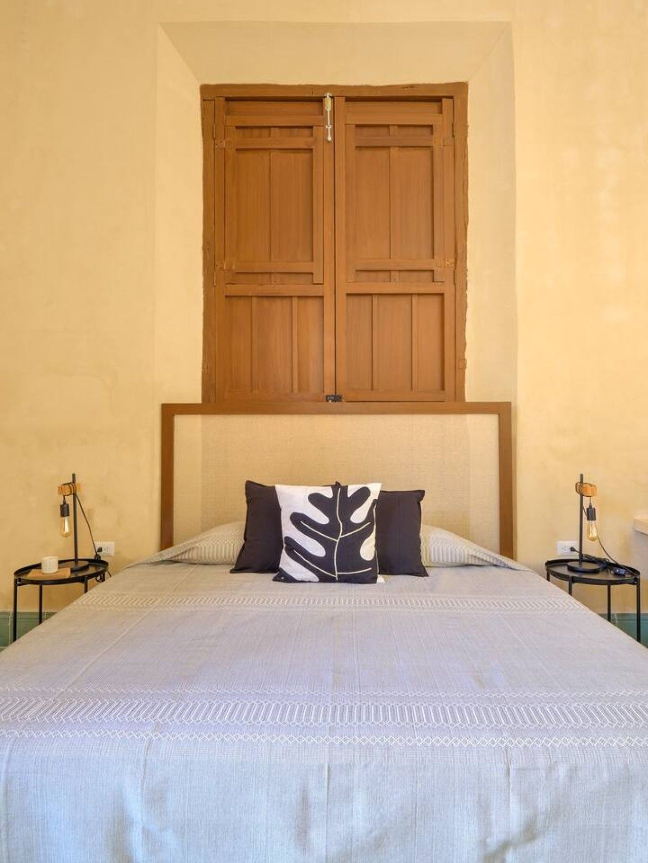 A bedroom with a large bed, two bedside tables, and a wooden wardrobe above the bed.